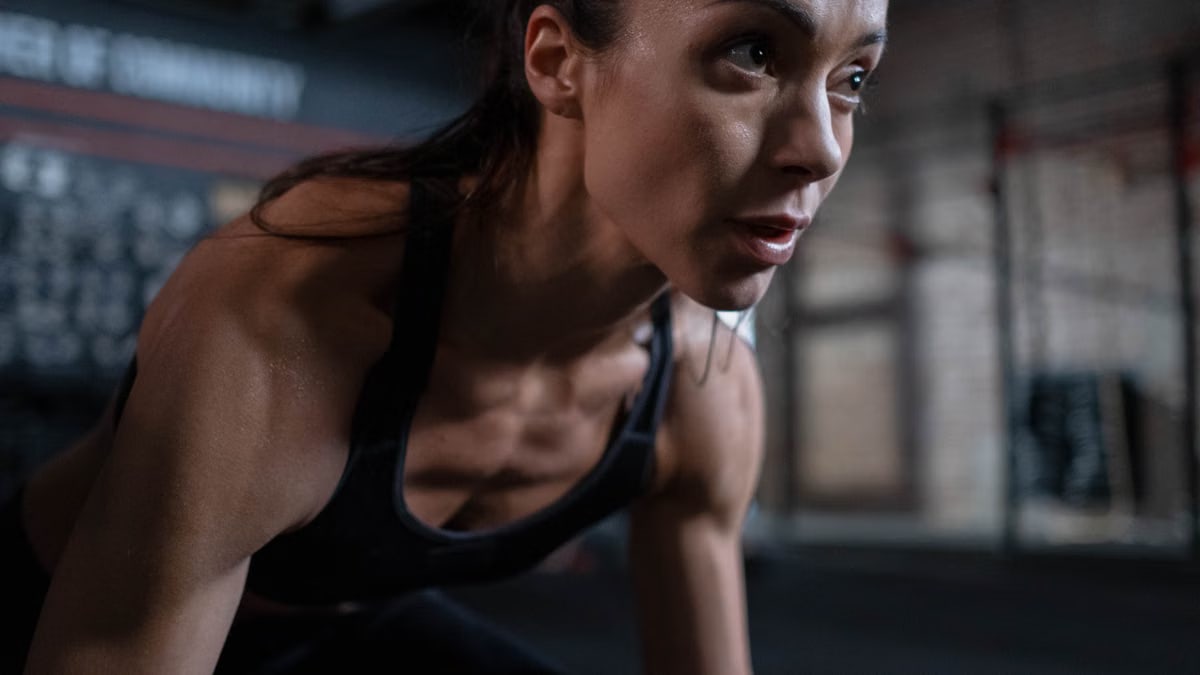 Close-up of a determined female athlete sweating during a workout session indoors.